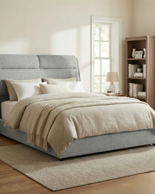 Gray upholstered bed with beige bedding in a bedroom setting.
