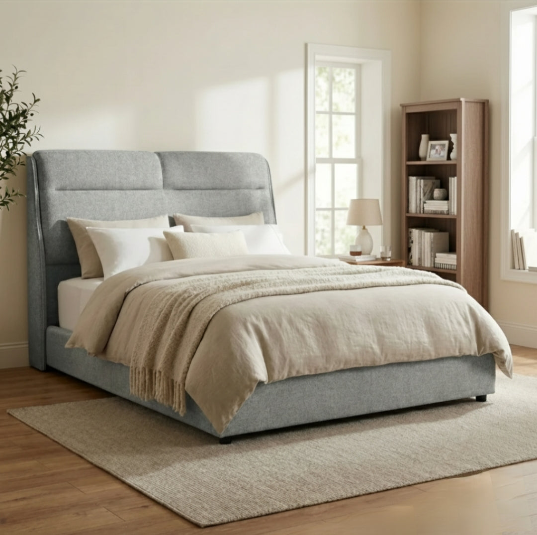 Gray upholstered bed with beige bedding in a bedroom setting.